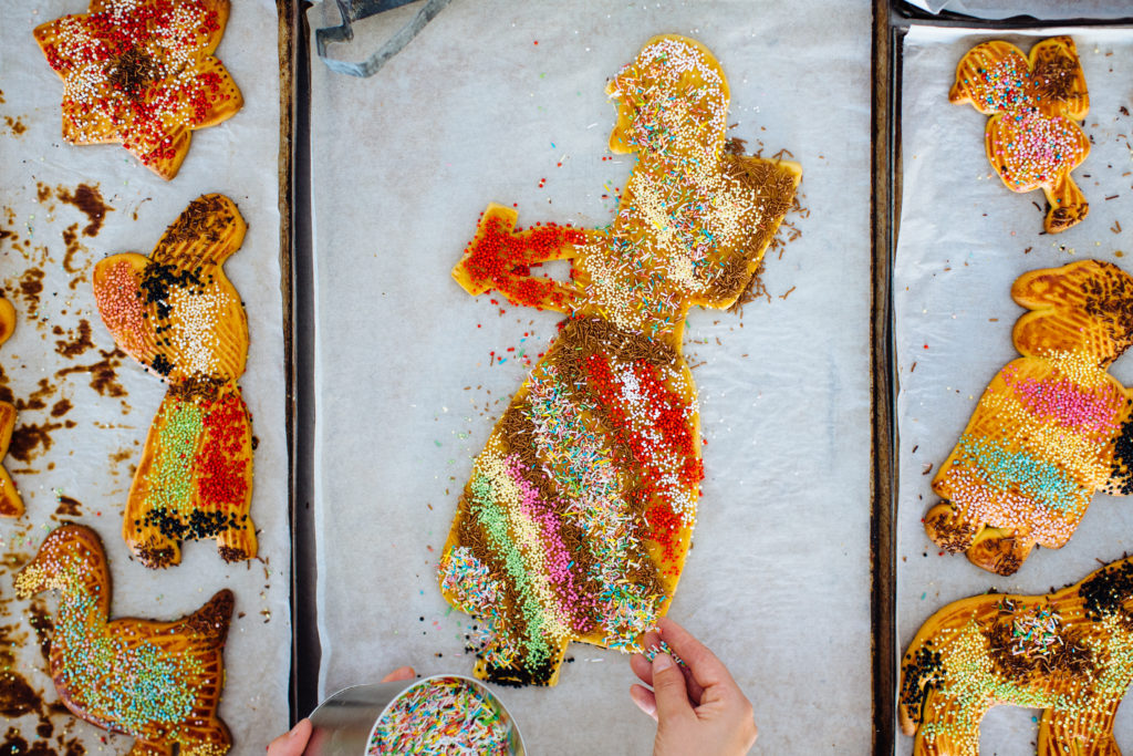 Hand scattering sprinkles on a big biscuit